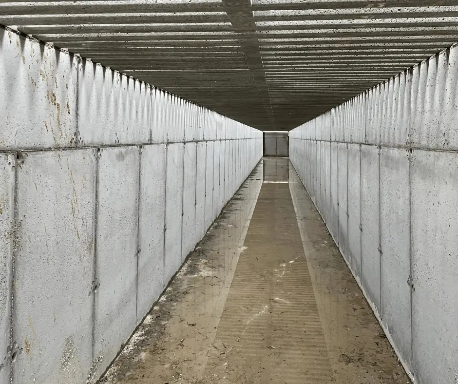 Widok wewnątrz wykonanego kanału betonowego stanowiącego część infrastruktury obiektu gospodarczego.
